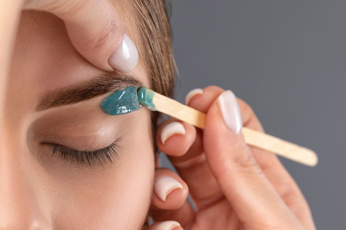 Warm wax being applied to shape an eyebrow